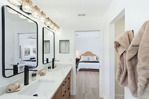 A modern bathroom with a large mirror, two sinks, and a towel rack. - 5bd Home w/ Pool, Home Theater, Kayak & Golf cart (Indian Rocks Beach)
