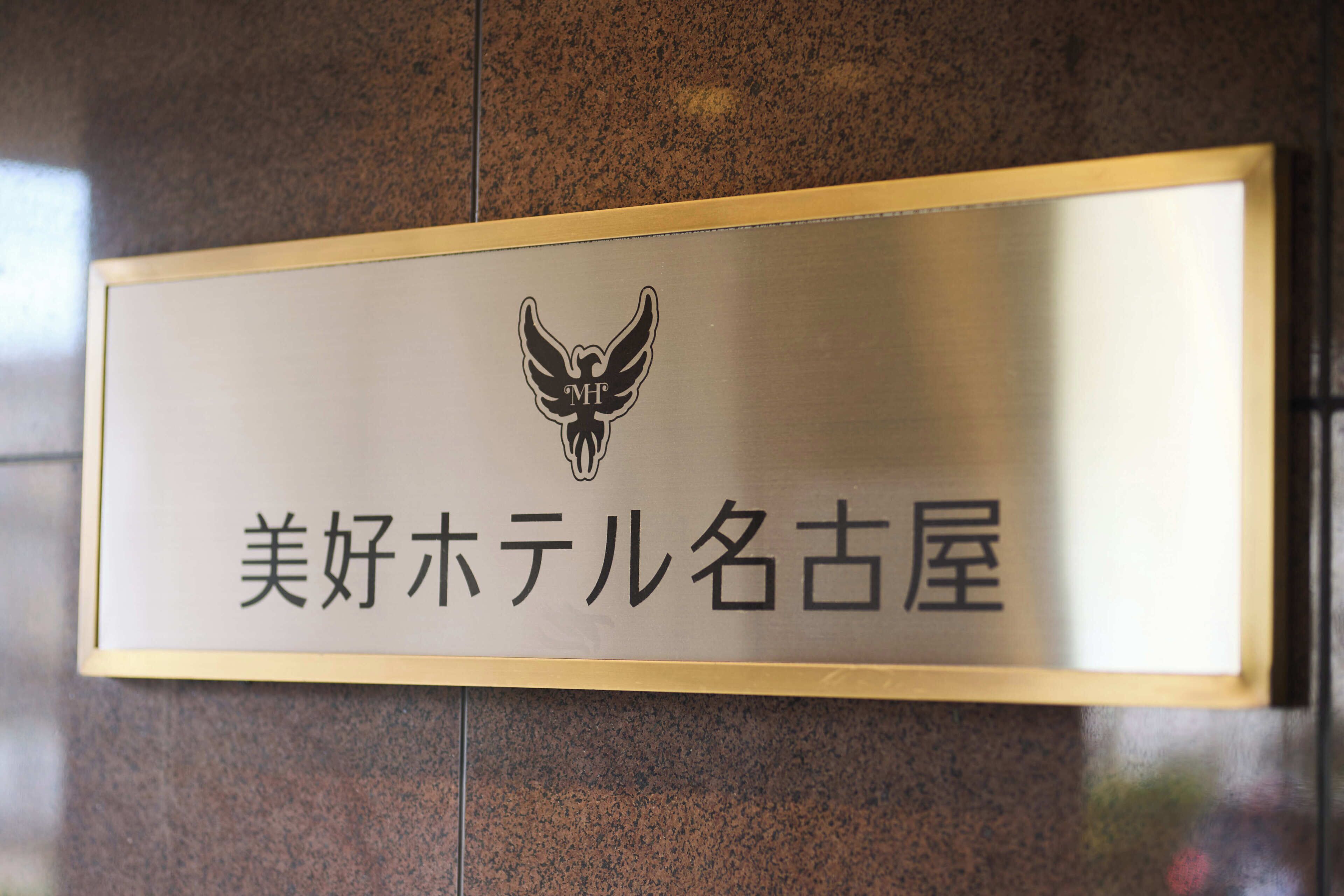 Un letrero con un logotipo y texto en japonés, fijado a una pared.