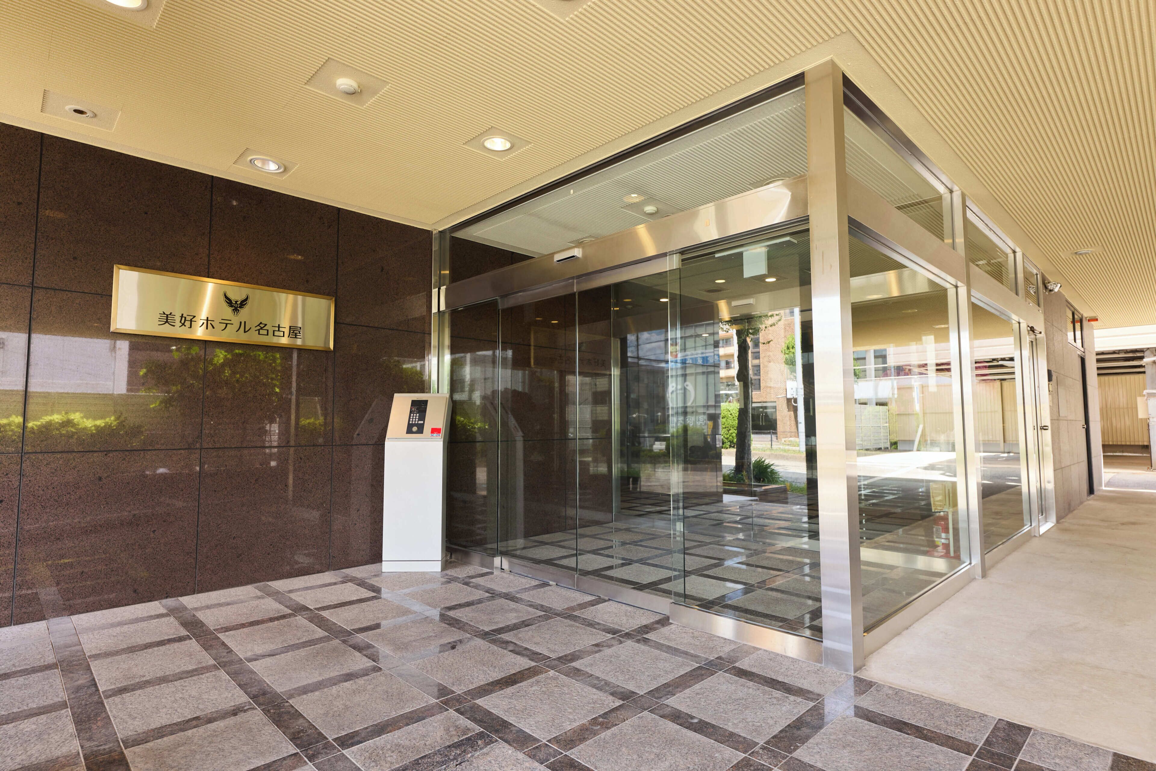 A modern building entrance with a glass door, a nameplate, and a keypad entry system.