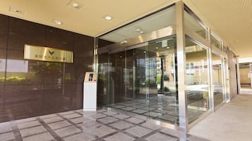 A modern building entrance with a glass door, a nameplate, and a keypad entry system.