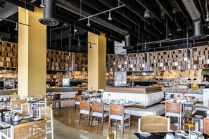 A modern restaurant with high ceilings, exposed ductwork, and a central bar area. - Garza Blanca Luxurious Oceanfront 3-Bedroom with Expansive Balcony and Jacuzzi (Cancún)