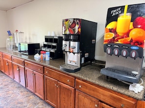 A coffee station with a coffee machine, a juice dispenser, and a condiment station.