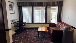 Una habitación con sofá, mesa, silla, radiador y cubo de basura.