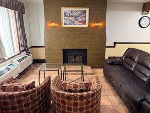 Una sala de estar con chimenea, un sofá, una mesa de centro y sillones estampados.