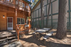 Eine Holzhütte mit Veranda, Gartenmöbeln im Freien und einem eingezäunten Hof.