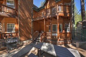Eine Blockhütte mit Veranda, Grill und Treppe zu einem Balkon.