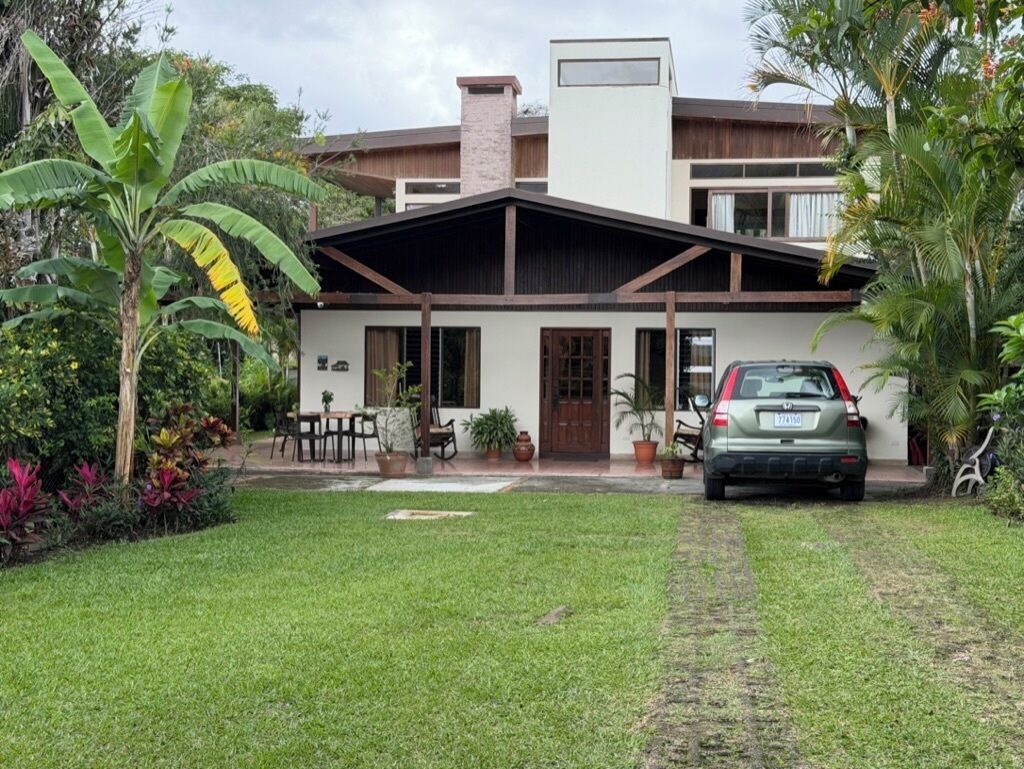 A modern house with a covered porch, a car parked in the driveway, and a well-maintained lawn.