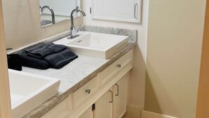 Un baño con lavamanos doble, un espejo, toallero y armario.