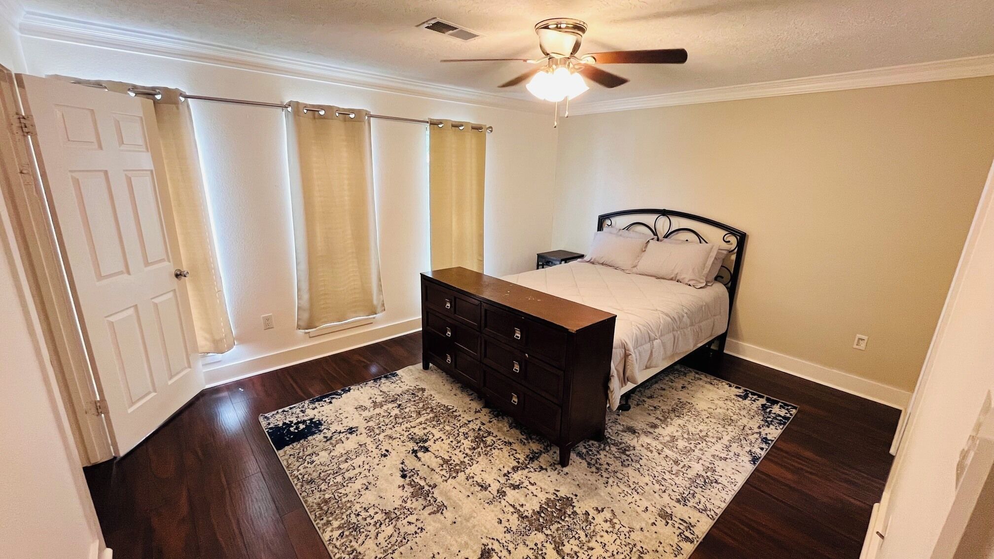 Une chambre à coucher avec un lit, une commode et un ventilateur de plafond.