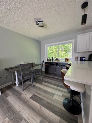A kitchen with a dining area, a window with a view of greenery, and a ceiling light fixture. - 3-bedrooms in quaint Dumfries with AC (Dumfries)