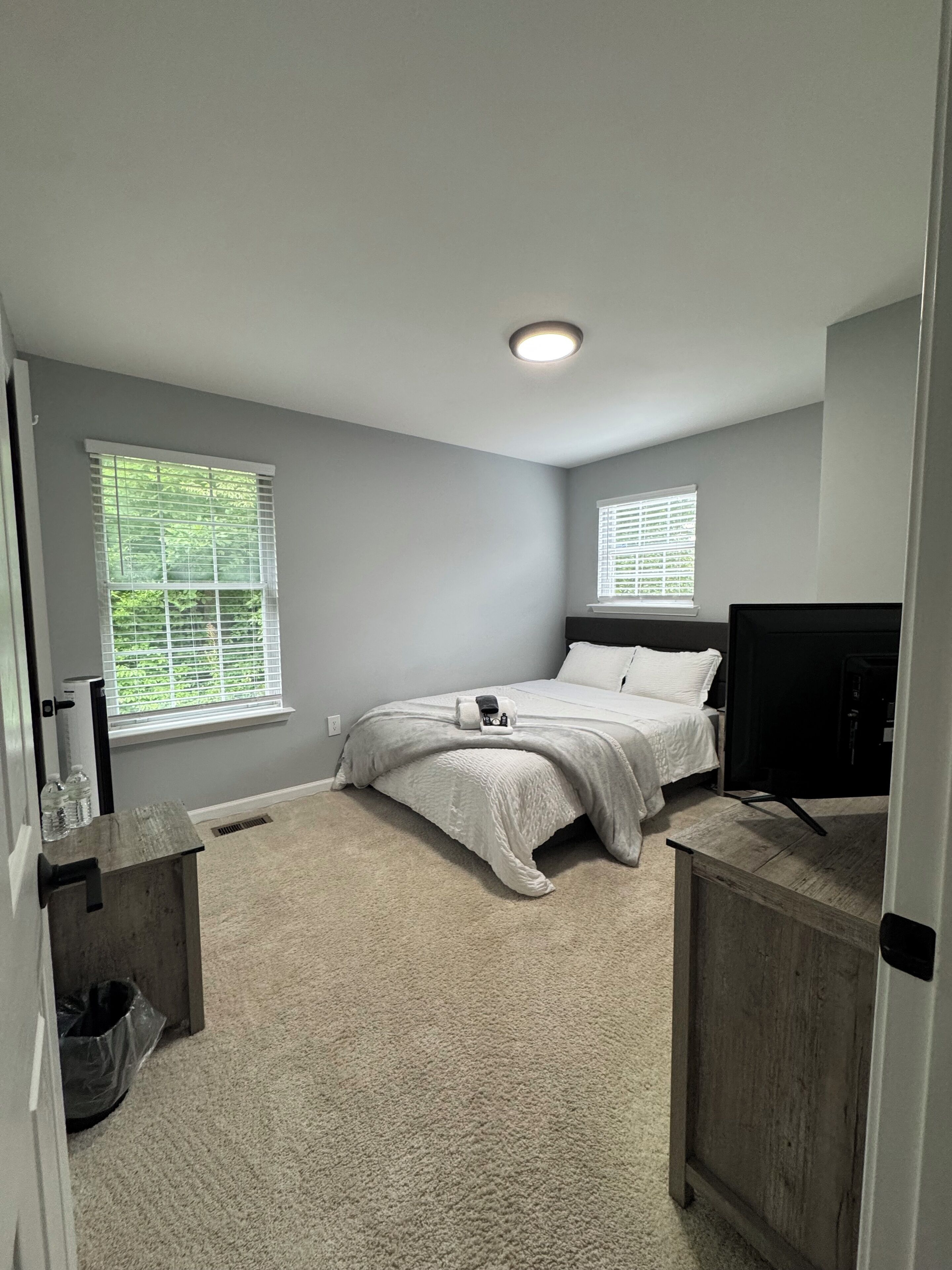 A bedroom with a bed, a TV, and a window.
