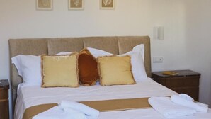 A neatly made bed with white bedding and a brown headboard, accompanied by three framed wall art pieces. - SYRENIA HOME (Vico Equense)