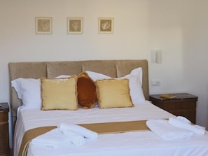 Ein ordentlich bezogenes Bett mit weißer Bettwäsche und einem braunen Kopfteil, ergänzt durch drei gerahmte Wandbilder.