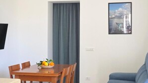 A room with a dining table set with a fruit bowl, a sofa, and a framed picture on the wall. - SYRENIA HOME (Vico Equense)