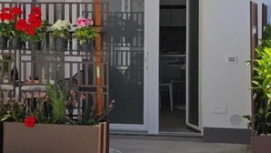 A building entrance with a covered patio area, a glass door, and a metal staircase. - SYRENIA HOME (Vico Equense)