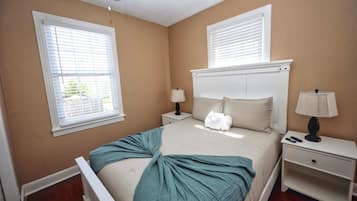 A bedroom with a bed, two bedside tables, a nightstand, and two lamps.
