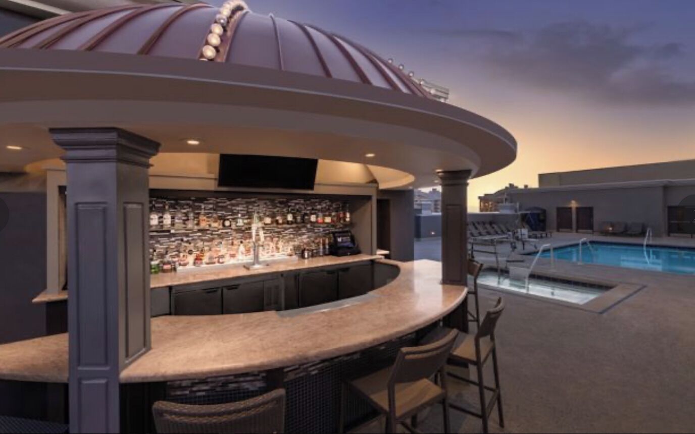 An outdoor bar area with a pool and lounge chairs.