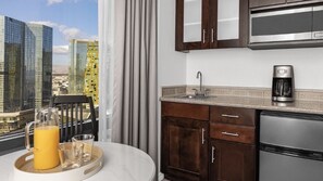 Une cuisine moderne avec vue sur la ville, une machine à café et un coin repas comprenant une table et des chaises.