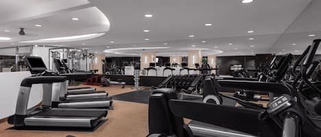 Une salle de sport moderne équipée de plusieurs tapis de course, d’appareils de musculation et d’un espace dédié aux exercices cardiovasculaires.