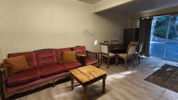 Un salon avec un canapé rouge, une table basse en bois et un coin repas comprenant des chaises et une table.