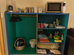 Una kitchenette con microondas, tostadora y licuadora sobre la encimera.