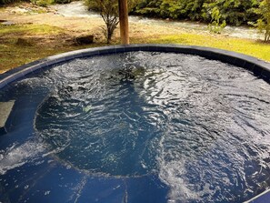 A swimming pool with clear water, surrounded by a grassy area and a small stream.