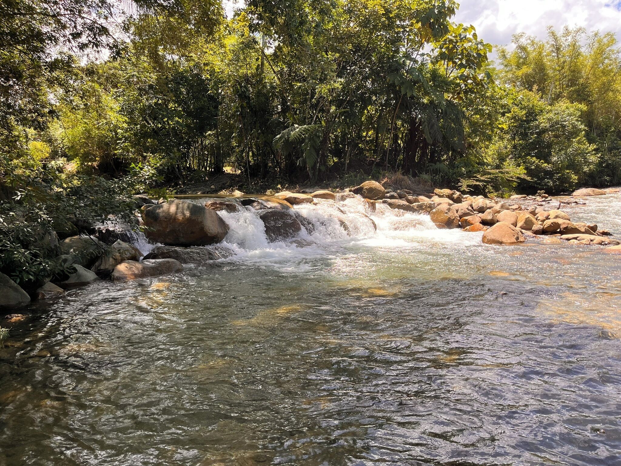 Una formación rocosa natural con una peque ña cascada rodeada de rocas y abundante vegetación.