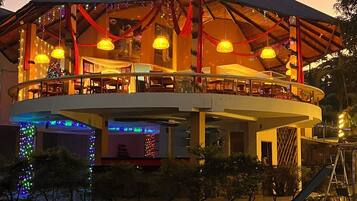 A two-story building with a covered patio area, outdoor seating, and a slide for children.