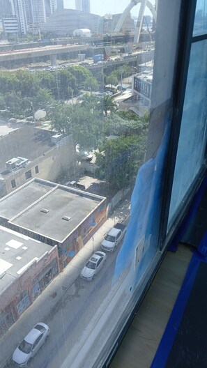 Blick aus einem Hochhausfenster auf eine belebte Stadtstraße mit mehreren Fahrspuren, einer Brücke und Hochhäusern.