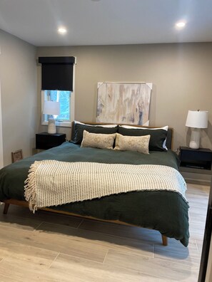 A modern bedroom with a large bed, a window with blinds, a wall-mounted artwork, and bedside lamps. - Luxury 3BR/3BA Basecamp Steps to Quicksilver Lift Main Street Dining Heated Pool (Breckenridge)