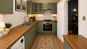 A compact kitchen with a washing machine, a stove, and a sink.