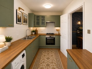 A compact kitchen with a washing machine, a stove, and a sink.