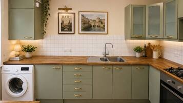 A compact kitchen with a washing machine, a sink, and a stove.