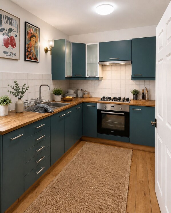 A modern kitchen with teal cabinets, a stainless steel sink, and a gas stove.