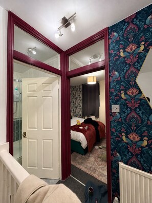 A bedroom with a bed, a mirror, and a door leading to a bathroom.