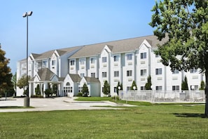 A large, multi-story hotel with a symmetrical facade, a covered entrance, and a fenced courtyard.