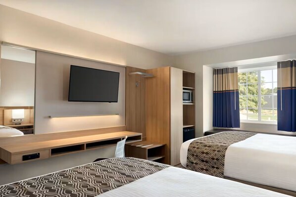 A hotel room with a bed, a TV mounted on the wall, a desk, and a wardrobe.