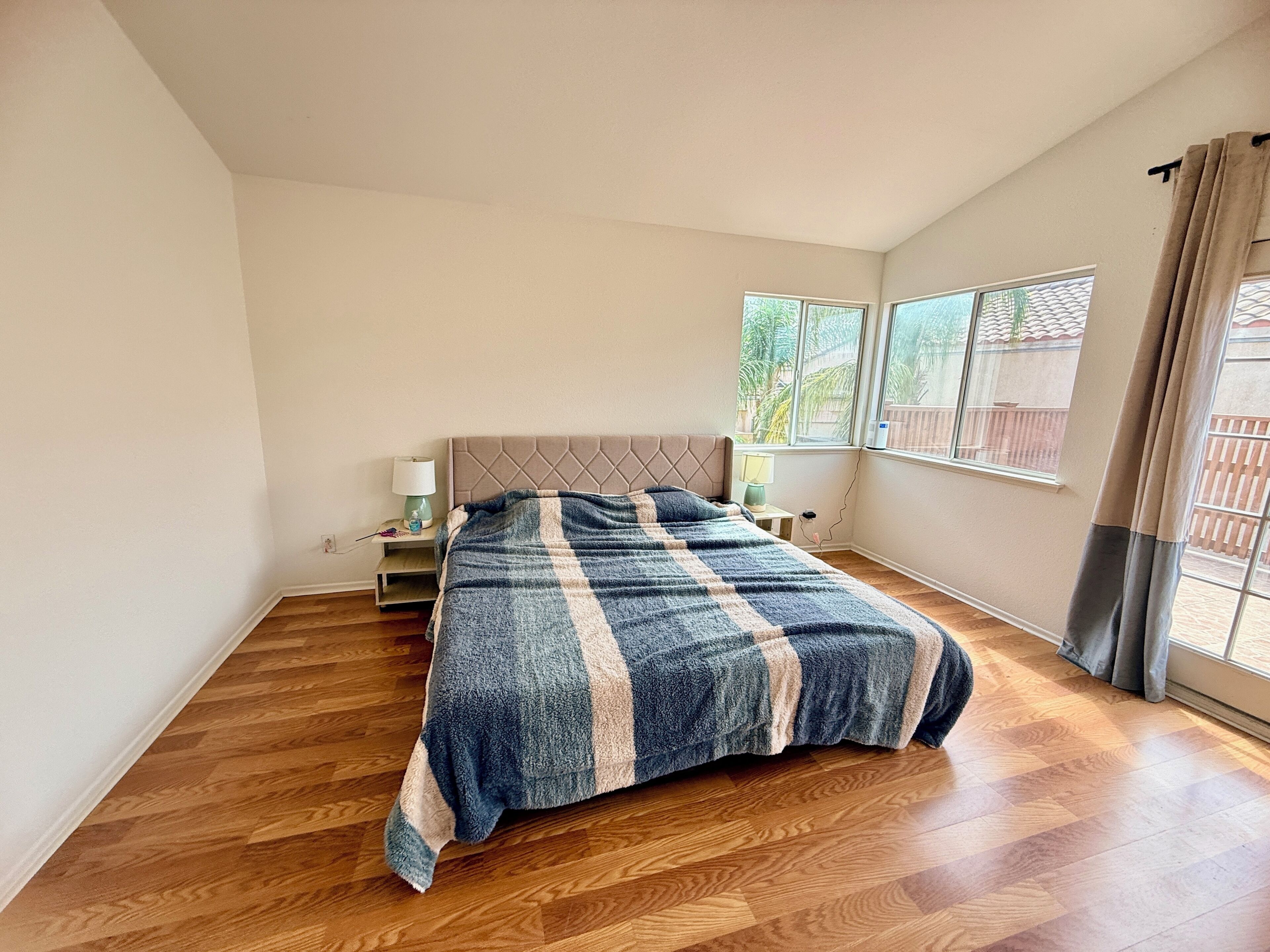 Ein Schlafzimmer mit einem Bett, einem Nachttisch, einem Fenster und Blick ins Freie.