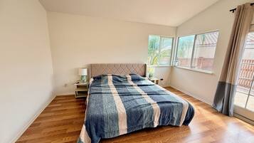 Ein Schlafzimmer mit einem Bett, einem Nachttisch, einem Fenster und Blick ins Freie.