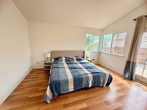 Un dormitorio con cama, mesita de noche, ventana y vistas al exterior.