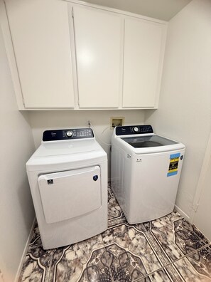 Un lavadero con dos lavadoras, una puerta y piso de baldosas.