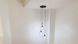Eine Treppe mit Holzhinweisstufen und weißen Geländern, die zu einer Zwischenebene mit einer weißen Wand und einer Deckenleuchte führt.