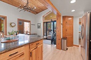 A modern kitchen with wooden cabinets, a granite countertop, and a built-in stainless steel refrigerator. - Perfect Moments at Moose Lodge Breckenridge Cabin on shuttle route (Breckenridge)