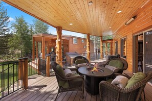 Eine überdachte Terrasse im Freien mit Korbmöbeln und einem zentralen Feuerbereich.