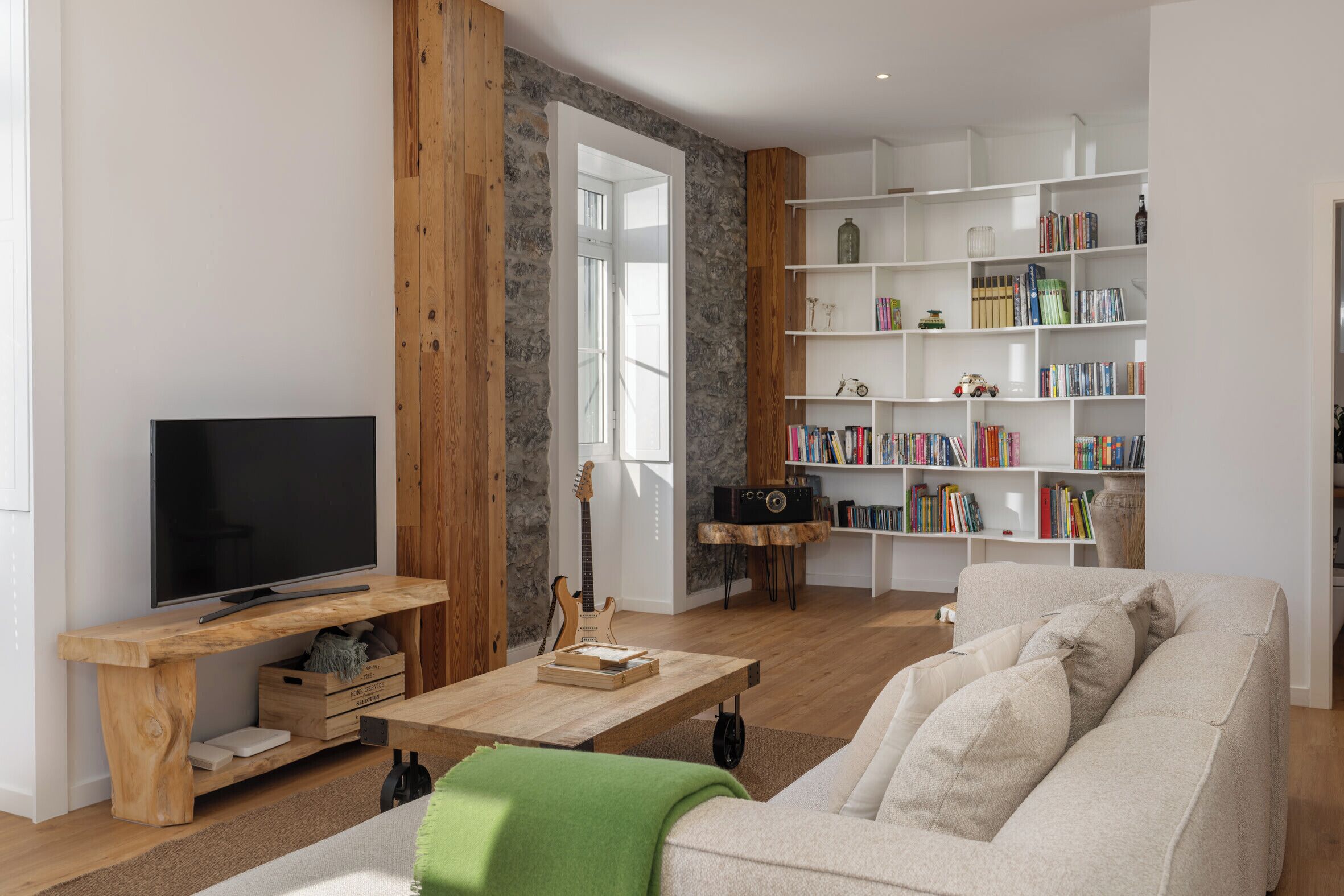 A living room with a television, wooden furniture, a bookshelf, and a sofa.