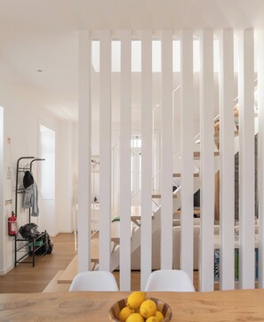 A modern interior with a wooden table, a fruit bowl, and a view of a staircase leading to a second floor. - Traditional House – Cozy 3-bedroom house (Funchal)