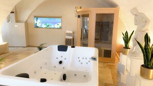 A spa room with a large bathtub, a wooden door, and a window with a view of the sea.