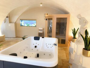 A spa room with a large bathtub, a wooden door, and a window with a view of the sea. - Venus • Private Spa, Jacuzzi & Sauna (L'Arbresle)