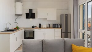 Una cocina moderna con armarios blancos, horno empotrado, microondas y refrigerador.