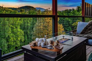 A wooden table with a tray of snacks and a chocolate bar, set against a scenic outdoor view. - Views, Indoor Pool & Game Room  1 Mi to Downtown (Gatlinburg)
